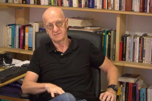 Dr. Andrej Perko, za njim knjižne police.